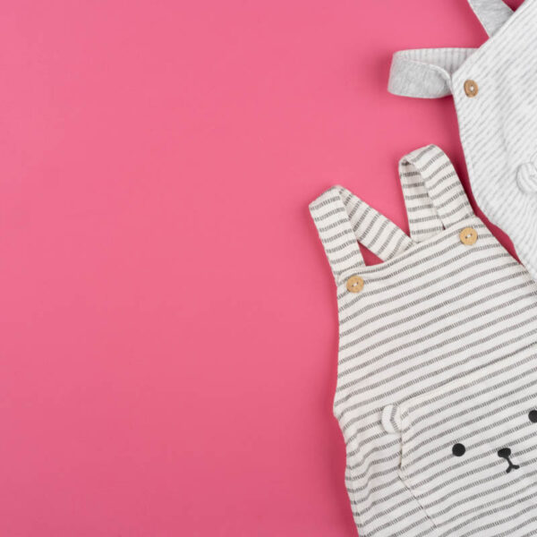 baby clothes on pink background top view